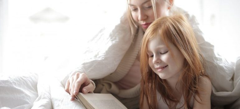 mother and daughter reading a book in bed