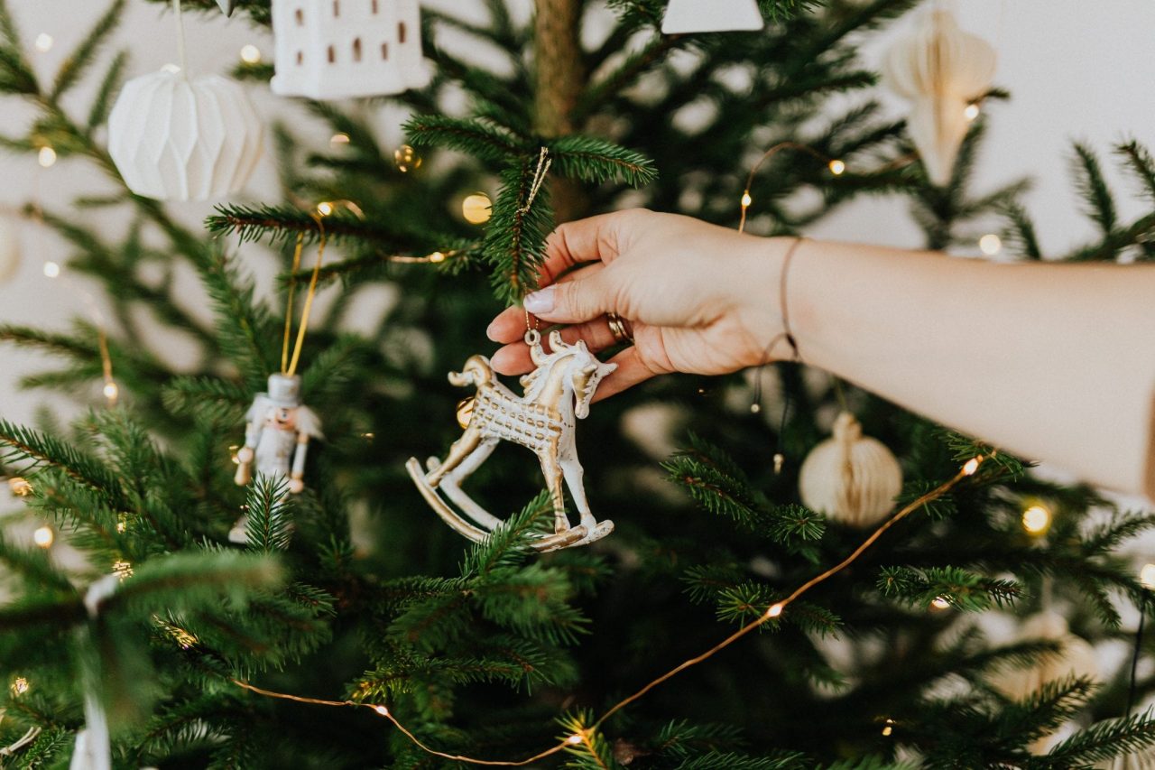 Hand taking down ornament from a tree is where you start storing Christmas decorations