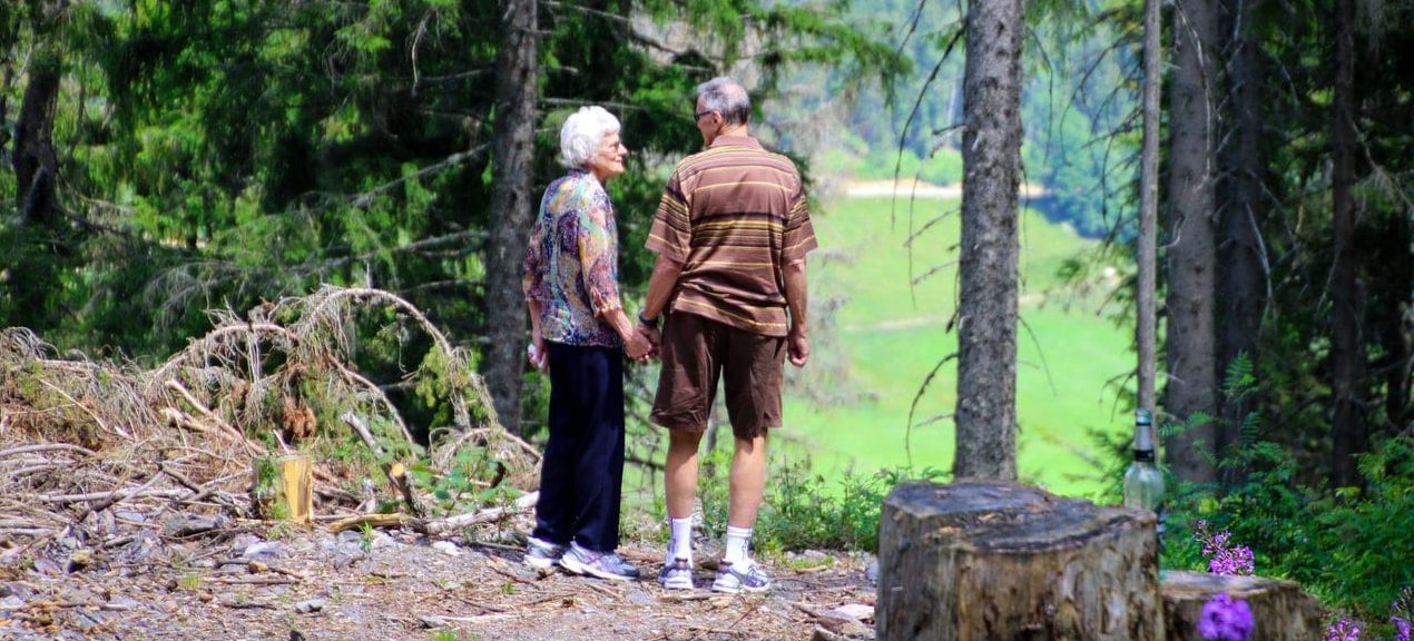 An elderly couple walking in the forest enjoying some of the nicest places in Kansas for retirement.
